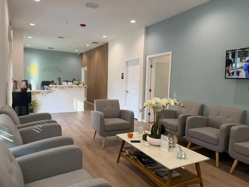 Modern waiting area at Bayside Dentistry in Sarasota, FL with gray chairs and wooden floor